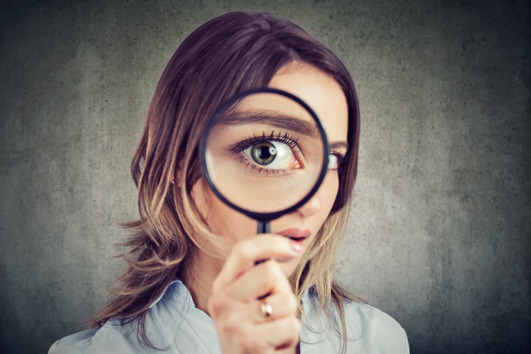 Curious woman looking through a magnifying glass