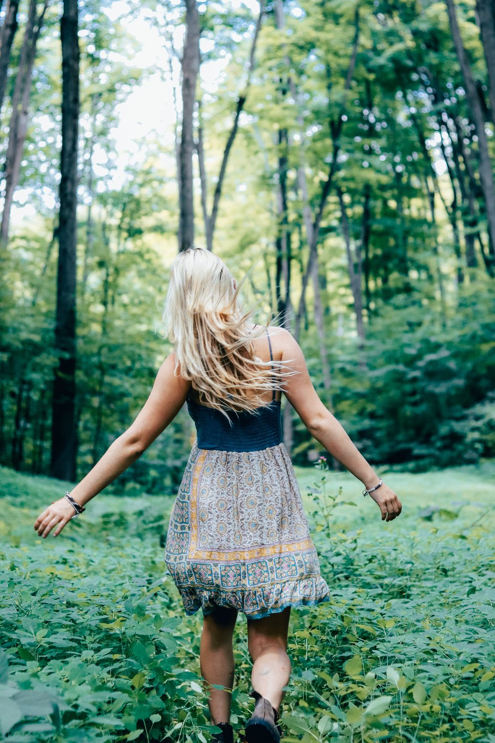 Blonde Woman Walking Through Green Forest